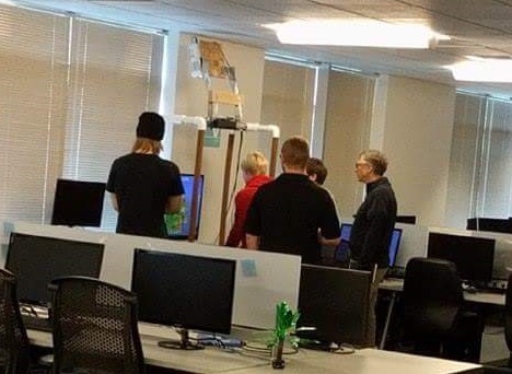 A blurry Bill Gates stands by admiring an early Sand Garden build. The janky construction looks like it could fall over at any moment, but everyone is engrossed in the game.