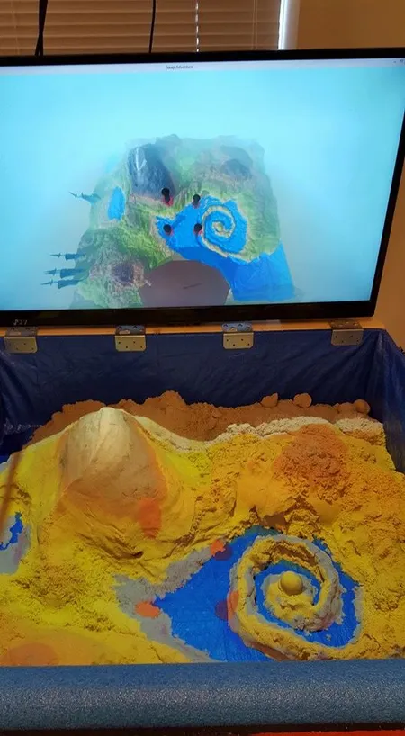 An early prototype of Sand Garden, showing a box of sand with a TV behind it that renders the game world